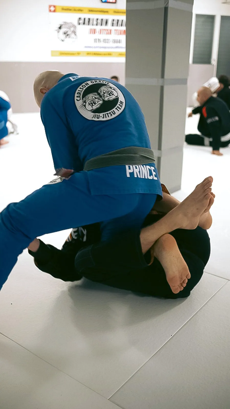Trainer passiert die Garde seines Partners, das Carlson-Gracie-Wappen auf dem Rücken
