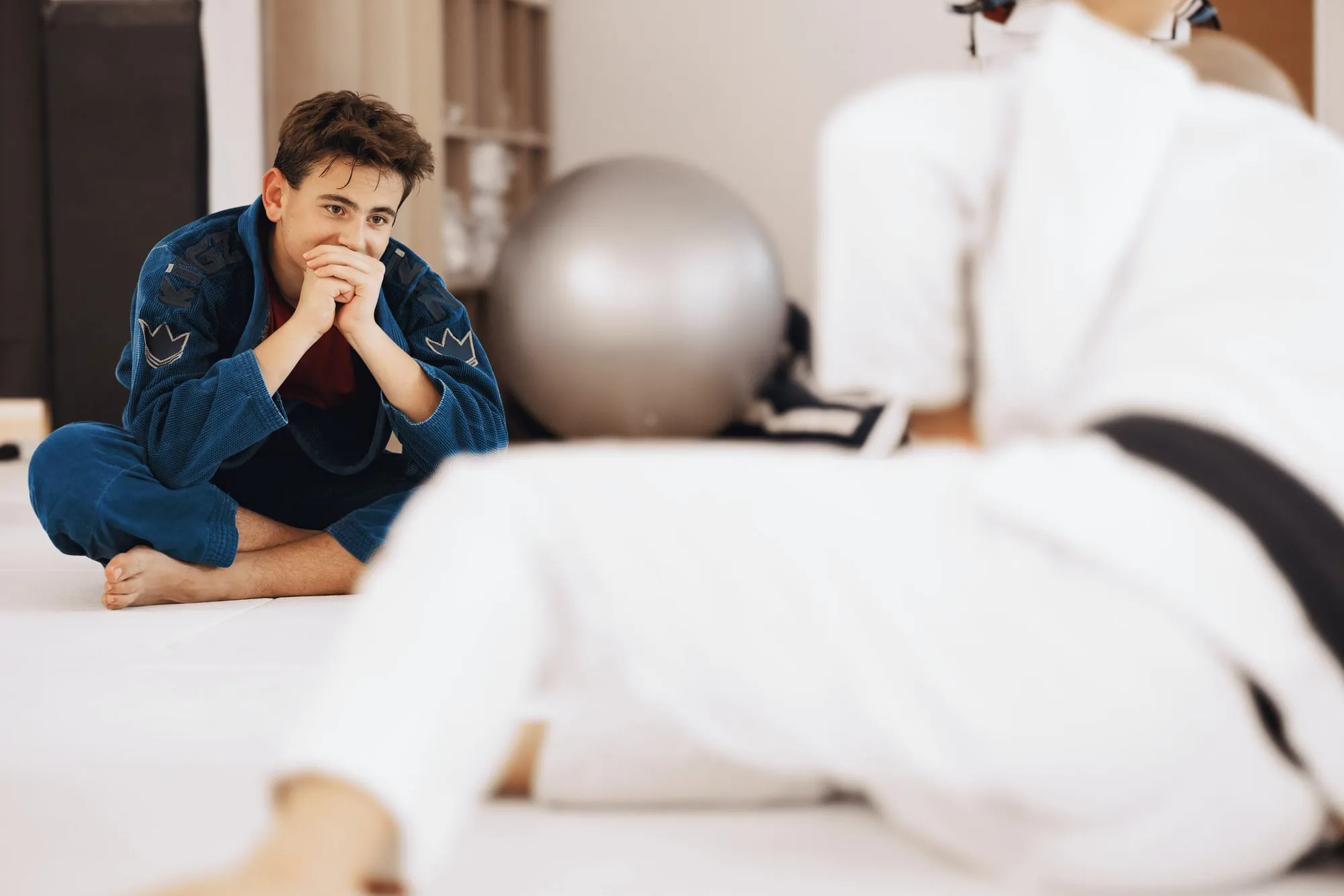 Trainierender im blauen Kimono verfolgt vom Mattenrand aus, was vorgezeigt wird